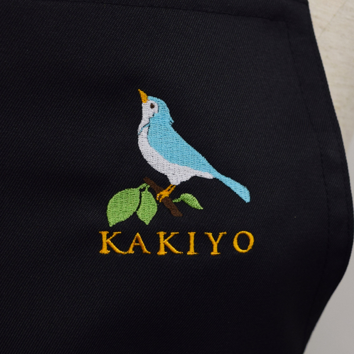 飲食店サービス制服刺繍実績　童画家のアトリエKAKIYO様(胸付きエプロン　ロゴ刺繍)